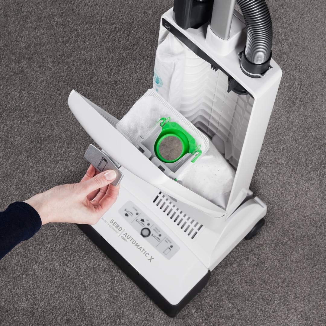 SEBO AUTOMATIC X4 Boost with front cover open, showing the genuine filter bag and green sealing collar; vacuum shown for fitment only